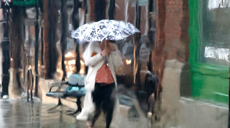 A woman with an umbrella is seen through a rain soaked window as she walks along South Fountain Avenue during a thunderstorm Tuesday, March 5, 2024. The sunshine and blue skies Tuesday morning quickly turned dark in the afternoon with a thunderstorm. BILL LACKEY/STAFF