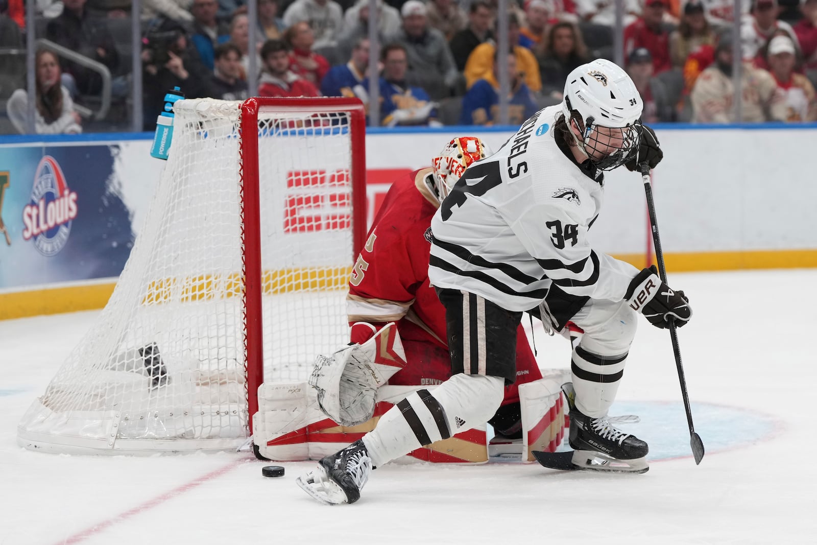 The puck slips past Western Michigan's Owen Michaels (34) as Denver goaltender Matt Davis defends during the first period in a semifinal game in the NCAA Frozen Four men's college hockey tournament, Thursday, April 10, 2025, in St. Louis (AP Photo/Jeff Roberson)