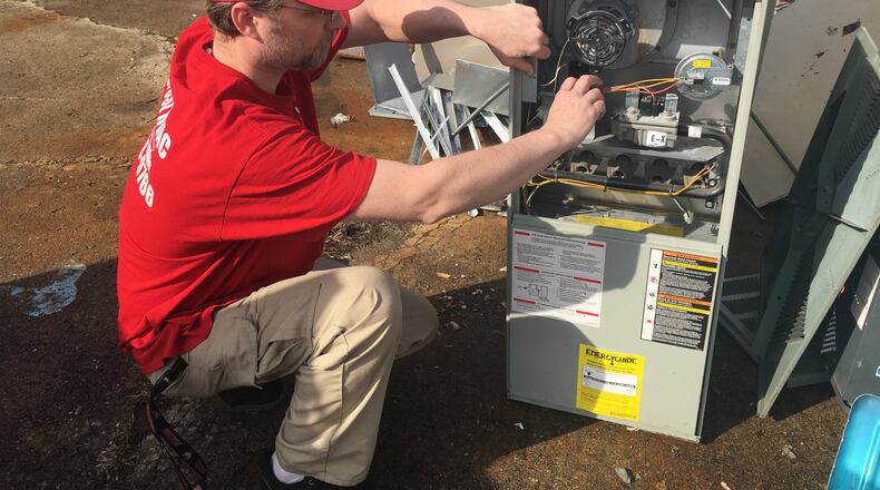 Jeremy Segrest, of Segrest HVAC, points out the problems of this heating unit. Allyson Brown/Staff