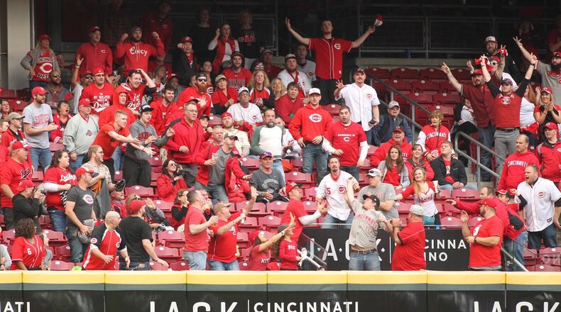 Fans try to catch a home run hit by the Reds’ Scooter Gennett in the ninth inning against the Phillies on Monday, April 3, 2017, at Great American Ball Park in Cincinnati.