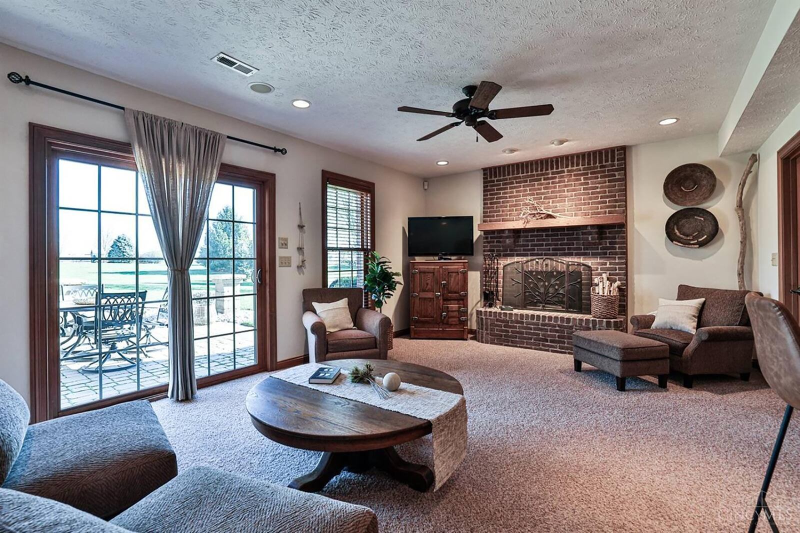 The basement family room has carpeting, a brick gas fireplace, ceiling fan and walks out to a paver patio and the back yard.