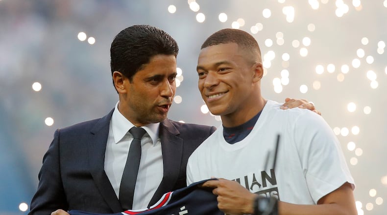 FILE - PSG President Nasser Al-Khelaifi, left, speaks to PSG's Kylian Mbappe as it is announced he has signed a three year extension to his contract, at the Parc des Princes stadium in Paris, France, Saturday, May 21, 2022. (AP Photo/Michel Spingler, File)