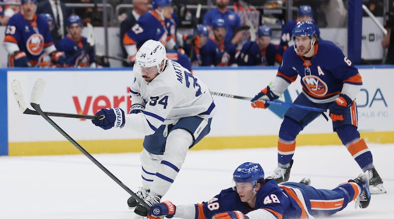 New York Islanders' Matthew Schaefer (48) reaches for the puck against Toronto Maple Leafs center Auston Matthews (34) during the first period of an NHL hockey game, Saturday, Jan. 3, 2026, in New York. (AP Photo/Heather Khalifa)