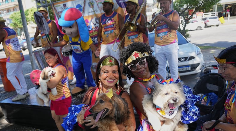 Owners and their pets pose for a photo at the "Blocao" Carnival dog parade in Rio de Janeiro, Saturday, Feb. 14, 2026. (AP Photo/Silvia Izquierdo)