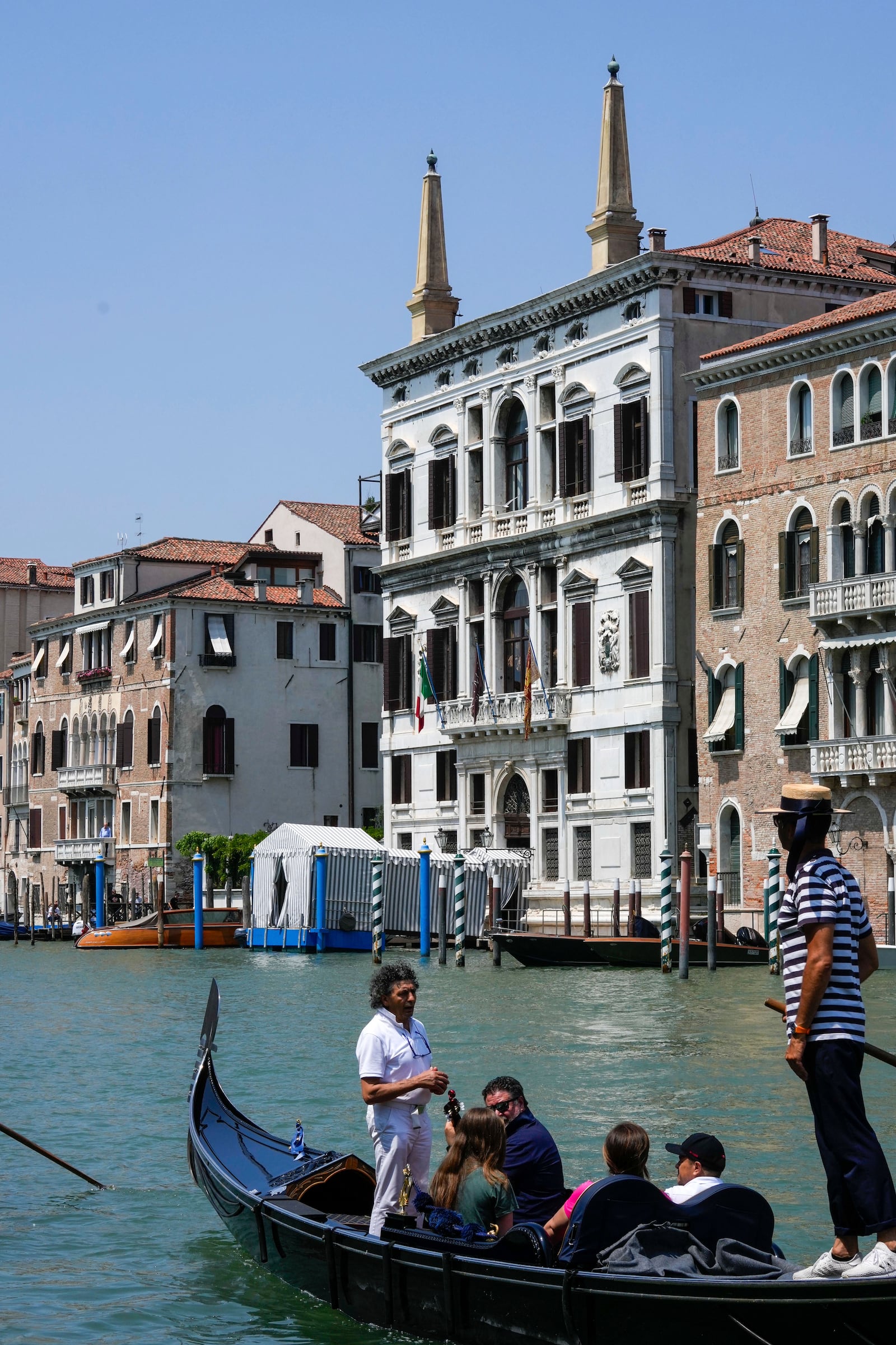 A gondola carries tourists in front of the Aman Hotel along the Grand Canal in Venice, Italy, on Wednesday, June 25, 2025, ahead of festivities in the lagoon city reportedly linked to a wedding celebration for Jeff Bezos and Lauren Sánchez. (AP Photo/Luca Bruno)