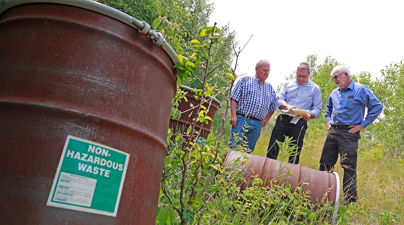 Bob Rule, from the "potential responsible party" group, center, along with German Township Trustee Rodney Kaffenbarger, left, and Larry Ricketts look over a map for the Tremont City Barrel Fill Wednesday, June 7, 2023. The barrels, at left, were empty but used during testing. BILL LACKEY/STAFF