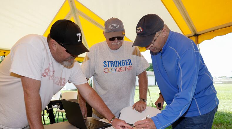 Chris Cory, left, Dale Steinlage, center, and Scott Griffith, strategize on where to place items on Thursday, June 19, 2025, as the prepare for an upcoming event at the Evans Family Ranch in New Carlisle. JOSEPH COOKE/STAFF