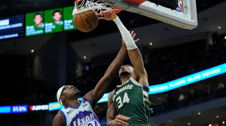 Milwaukee Bucks' Giannis Antetokounmpo, right, dunks over Utah Jazz's Oscar Tshiebwe, left, during the second half of an NBA basketball game Saturday, March 7, 2026, in Milwaukee. (AP Photo/Aaron Gash)