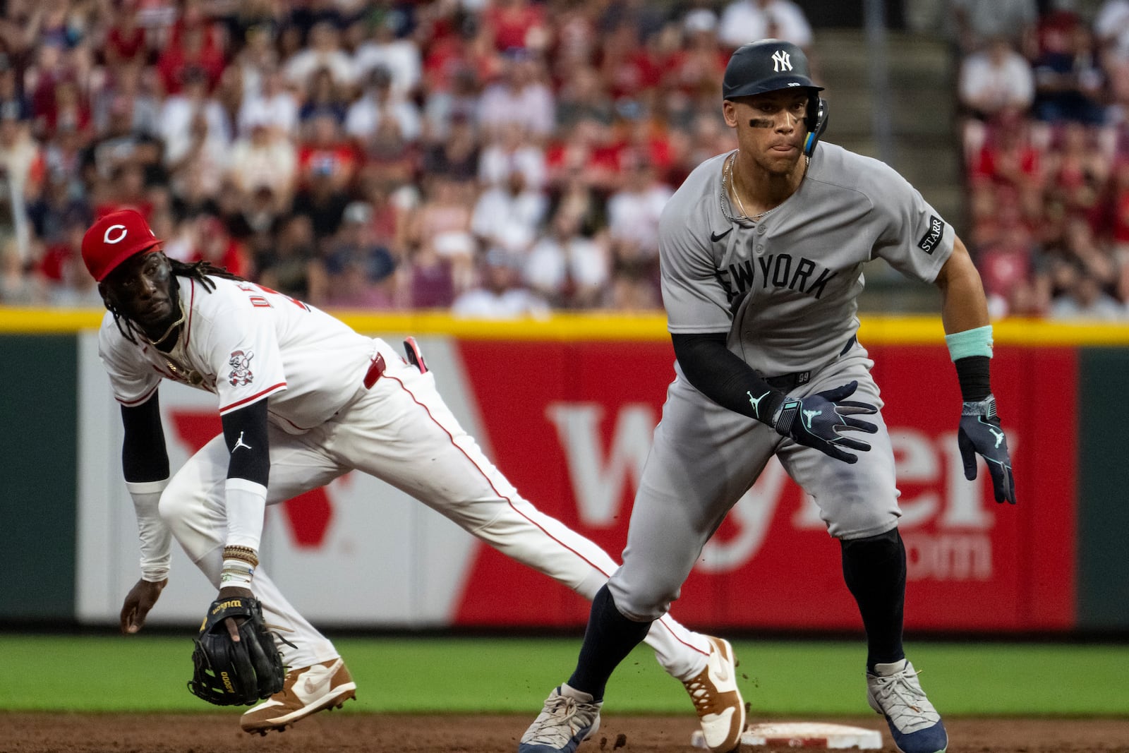 New York Yankees' Aaron Judge runs towards third base as Cincinnati Reds shortstop Elly De La Cruz lunges towards a ground ball in the fifth inning of a baseball game Wednesday, June 25, 2025, in Cincinnati. (AP Photo/Michael Swensen)