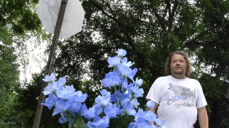 Fred Duffey looks over the small flowers placed on the corner of Rice and Josephine streets in remembrance of James Mundy, who was shot and killed there Monday night. Duffey was the first to find Mundy and tried to take care of him till medics arrived. Bill Lackey/Staff