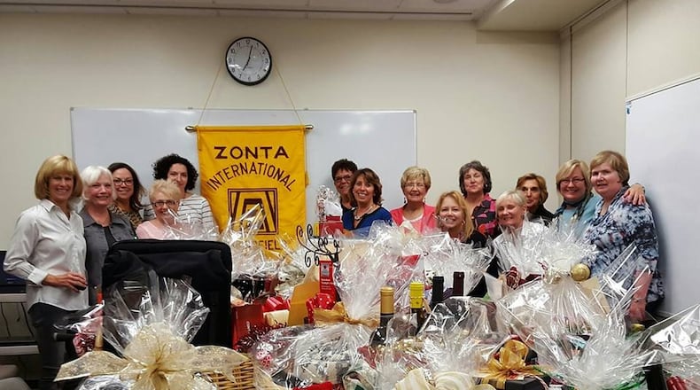 Zonta Club members stand behind a large collection of gift baskets auctioned off at a previous Zonta Holiday Auction. CONTRIBUTED