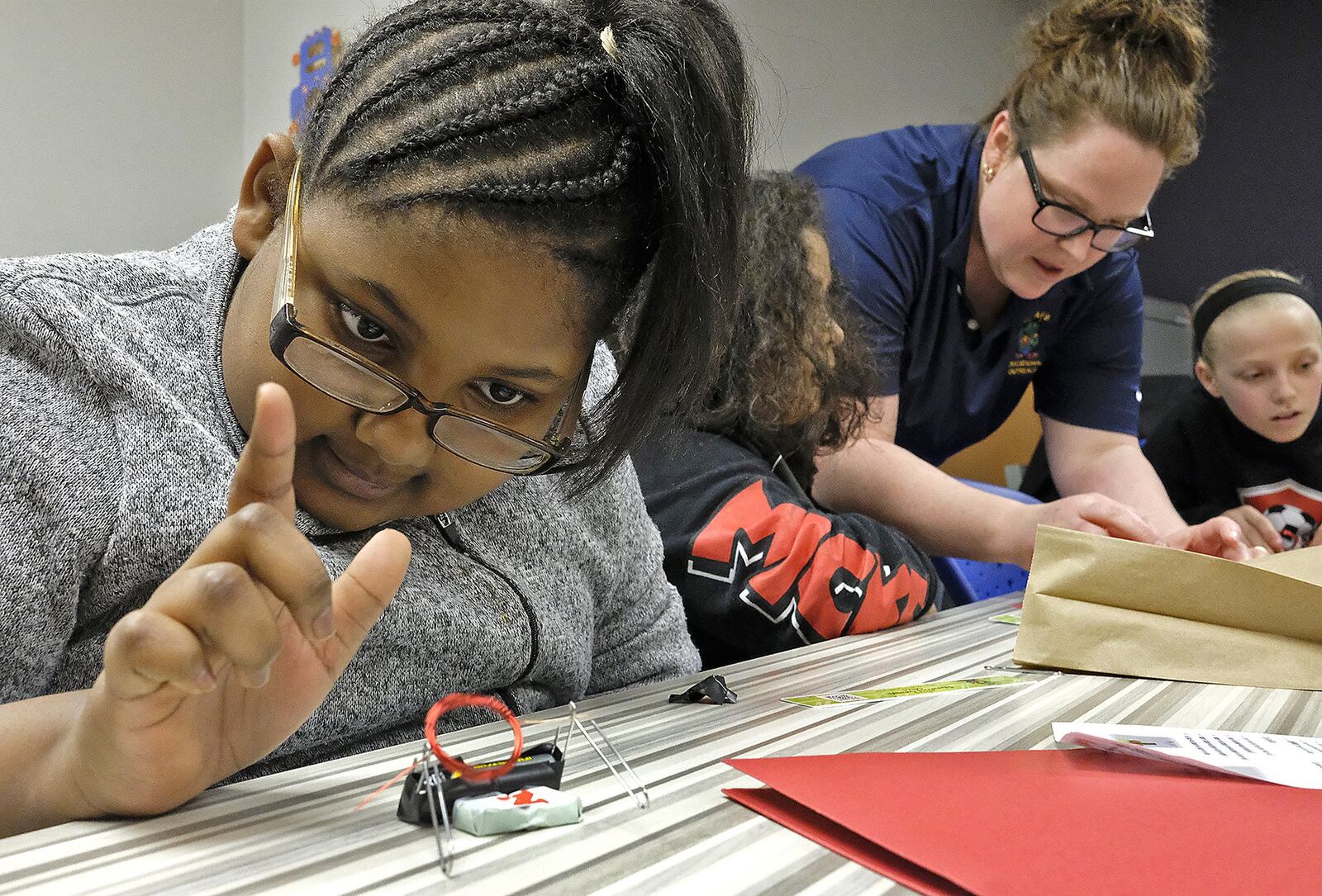 Jadie Welliford, a fourth grader, plays with the electric motor she made as Dr. Amanda King helps another student during one of the breakout sessions at the Springfield City Schools’ STEM program for girls Monday evening. Bill Lackey/Staff