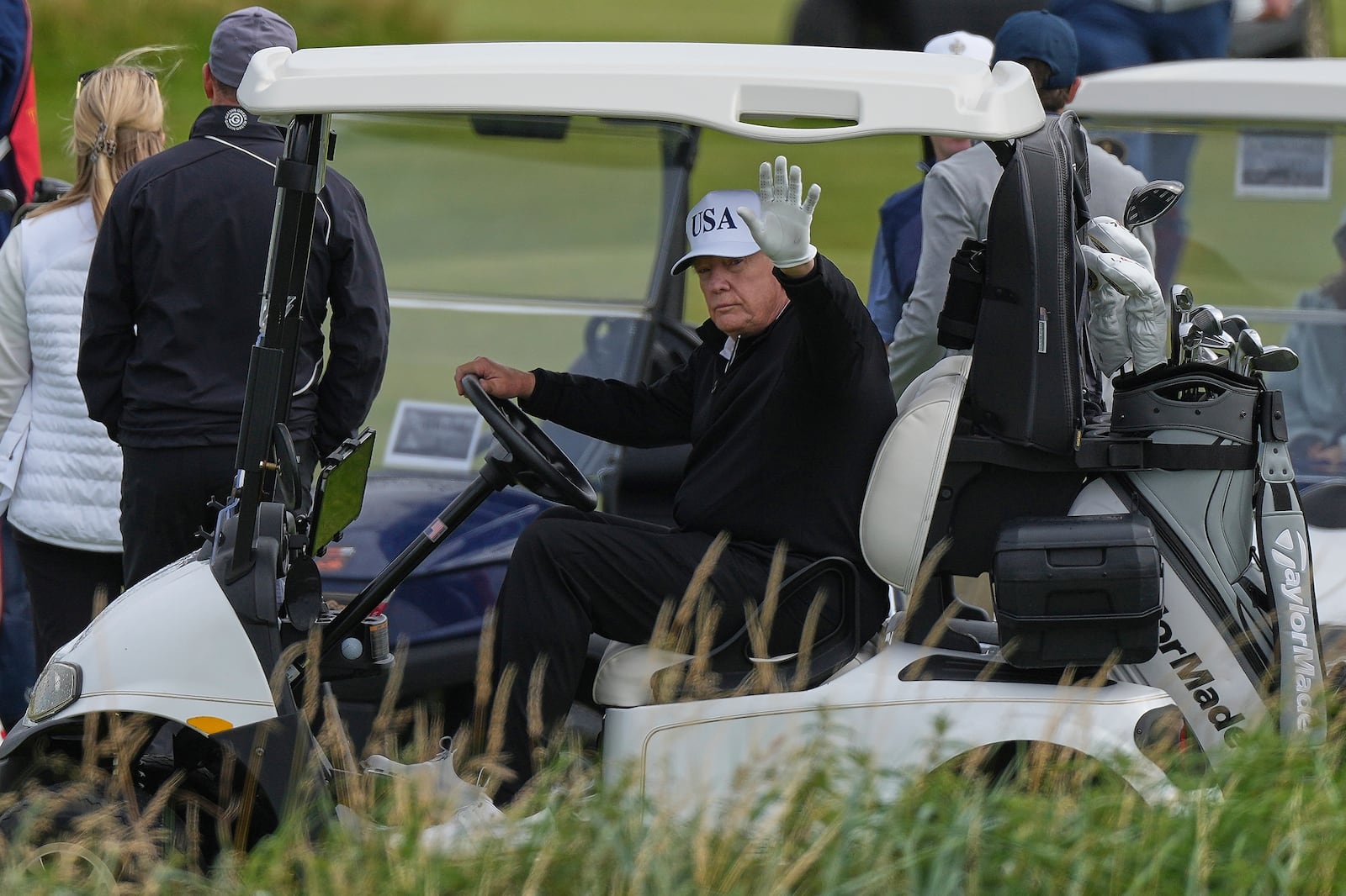 President Donald Trump waves to reporters as he sits in his golf cart at the Trump Turnberry golf course in Turnberry, Scotland, Saturday, July 26, 2025.(AP Photo/Alastair Grant)