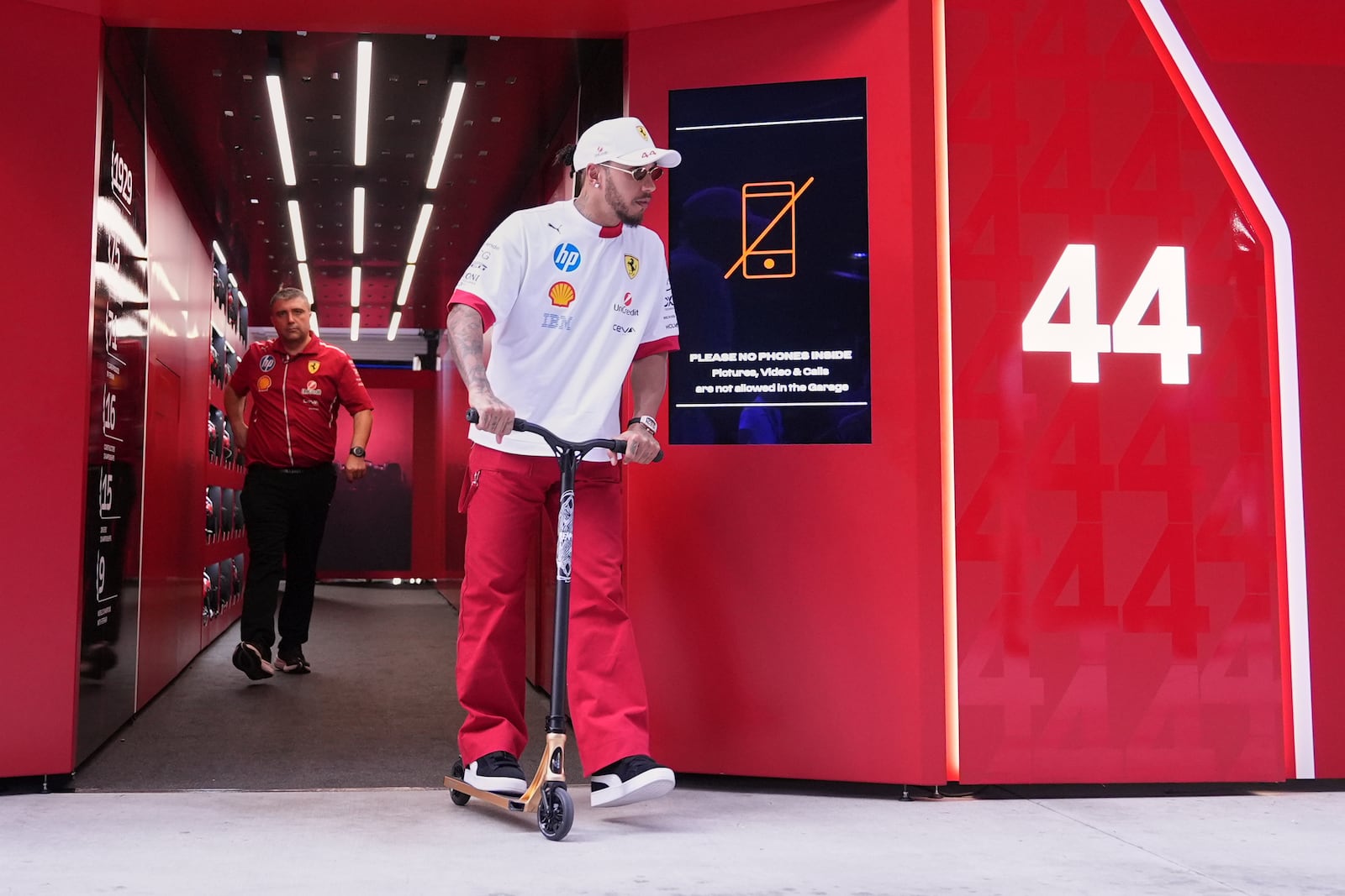 Ferrari driver Lewis Hamilton, of Britain, rides a scooter as he leaves the Ferrari garage ahead of the Formula One Miami Grand Prix auto race, Thursday, May 1, 2025, in Miami Gardens, Fla. (AP Photo/Rebecca Blackwell)
