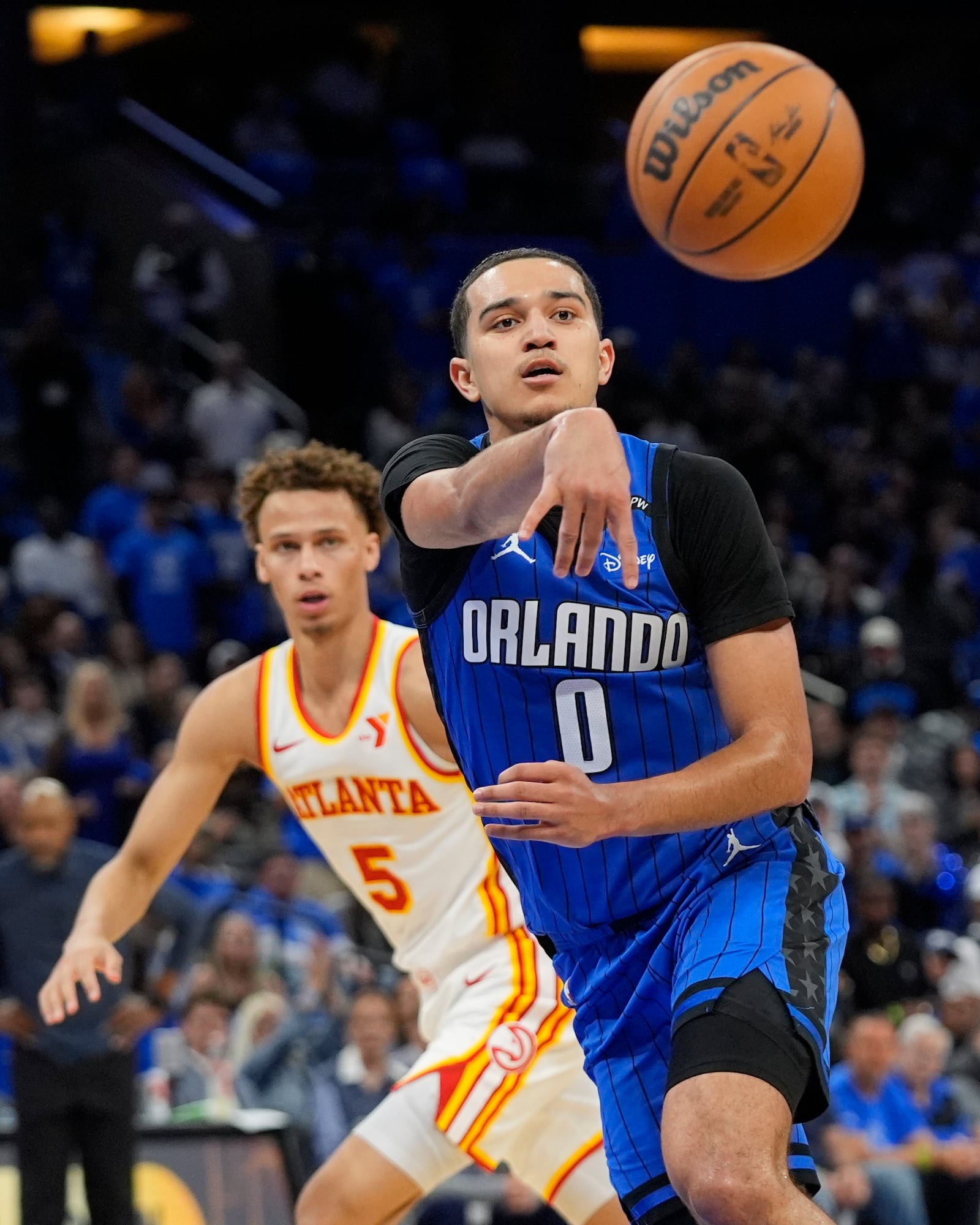 Orlando Magic guard Anthony Black (0) passes the ball in front of Atlanta Hawks guard Dyson Daniels (5) during the second half of an NBA play-in tournament basketball game, Tuesday, April 15, 2025, in Orlando, Fla. (AP Photo/John Raoux)
