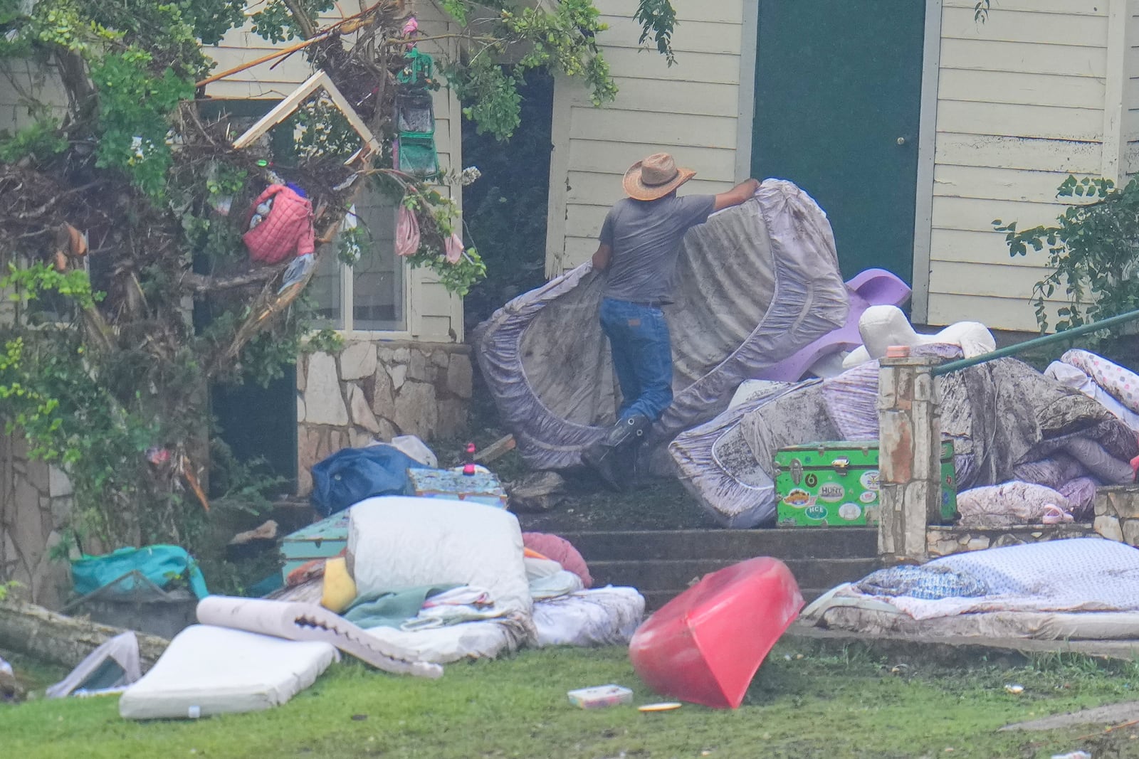 A person removes bedding from sleeping quarters at Camp Mystic along the banks of the Guadalupe River after a flash flood swept through the area Sunday, July 6, 2025, in Hunt, Texas. (AP Photo/Julio Cortez)
