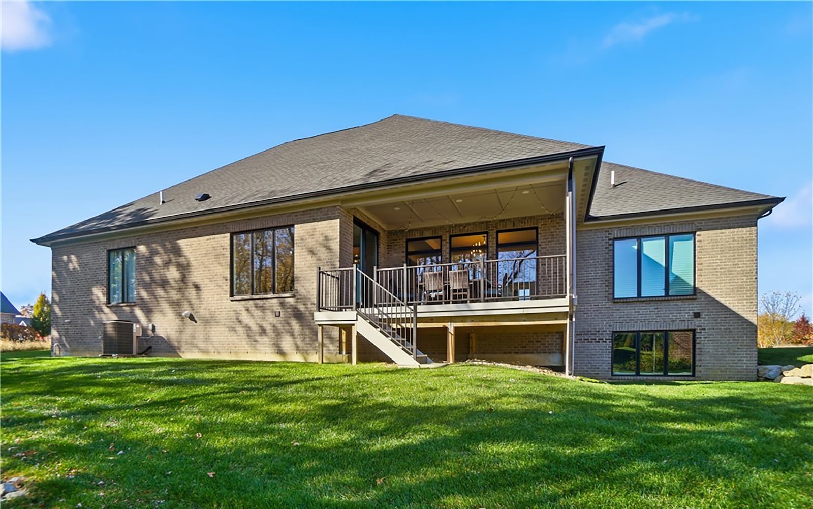 The back of the home features a covered deck with stairs leading down to the yard, which is tree lined. CONTRIBUTED