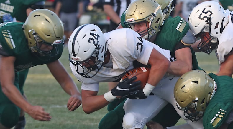 Greenon's Trevor Stewart is tackled by a pack of Catholic Central defenders Friday. BILL LACKEY/STAFF