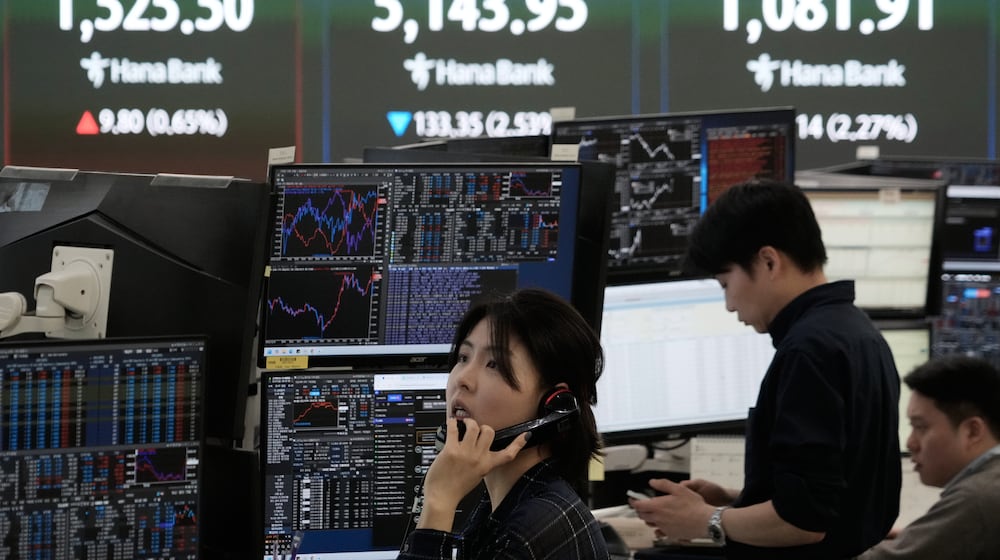 A currency trader talks on the phone near a screen showing the Korea Composite Stock Price Index (KOSPI), top center, and the foreign exchange rate between U.S. dollar and South Korean won, top center left, at the foreign exchange dealing room of the Hana Bank headquarters in Seoul, South Korea, Tuesday, March 31, 2026. (AP Photo/Ahn Young-joon)