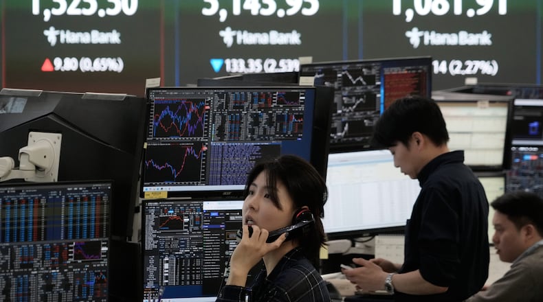 A currency trader talks on the phone near a screen showing the Korea Composite Stock Price Index (KOSPI), top center, and the foreign exchange rate between U.S. dollar and South Korean won, top center left, at the foreign exchange dealing room of the Hana Bank headquarters in Seoul, South Korea, Tuesday, March 31, 2026. (AP Photo/Ahn Young-joon)