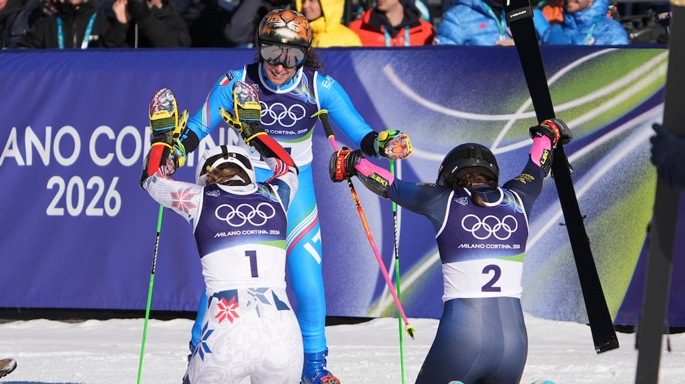 Sweden's Sara Hector, right, and Norway's Thea Louise Stjernesund bow to Italy's Federica Brignone, center, at the finish area of an alpine ski, women's giant slalom race, at the 2026 Winter Olympics, in Cortina d'Ampezzo, Italy, Sunday, Feb. 15, 2026. (AP Photo/Jacquelyn Martin)