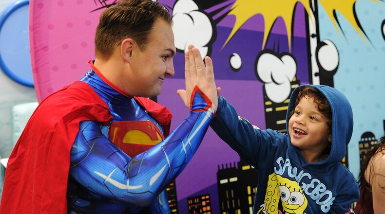Messiah Stinson, age 3, high-fives Superman on Wednesday, Jan. 31, 2024 at the 11th annual Superhero Day at Dayton Children’s Hospital. The tradition honors a patient who loved superheroes. The event recognizes other superheroes too — the patients, families, caregivers and staff at Dayton Children’s Hospital. MARSHALL GORBY\STAFF