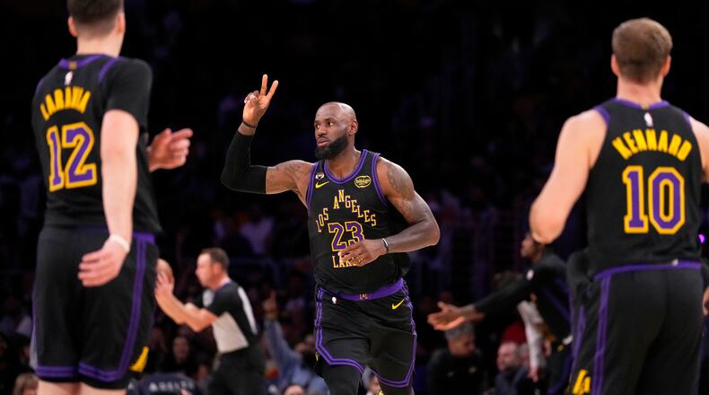 Los Angeles Lakers forward LeBron James, center, gestures after scoring as Los Angeles Lakers forward Jake LaRavia, left, and guard Luke Kennard watch during the first half of an NBA basketball game Tuesday, March 3, 2026, in Los Angeles. (AP Photo/Mark J. Terrill)