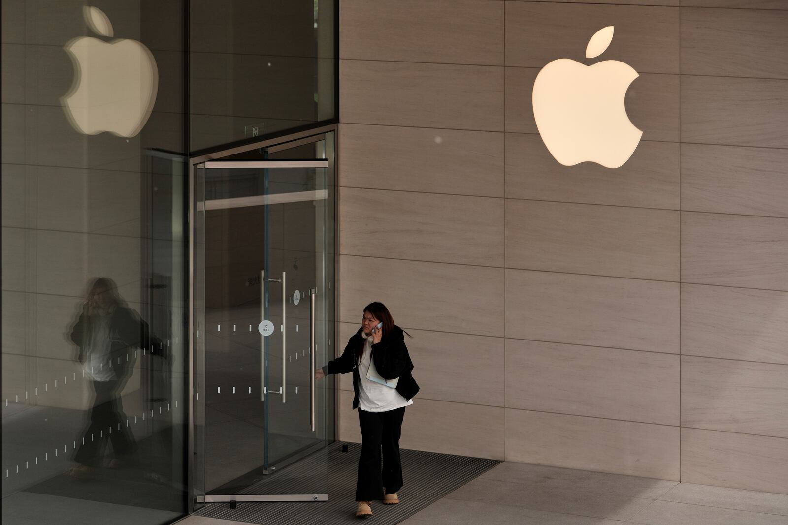 A woman walks out from an Apple Store at an outdoor shopping mall in Beijing, Tuesday, April 8, 2025. (AP Photo/Andy Wong)