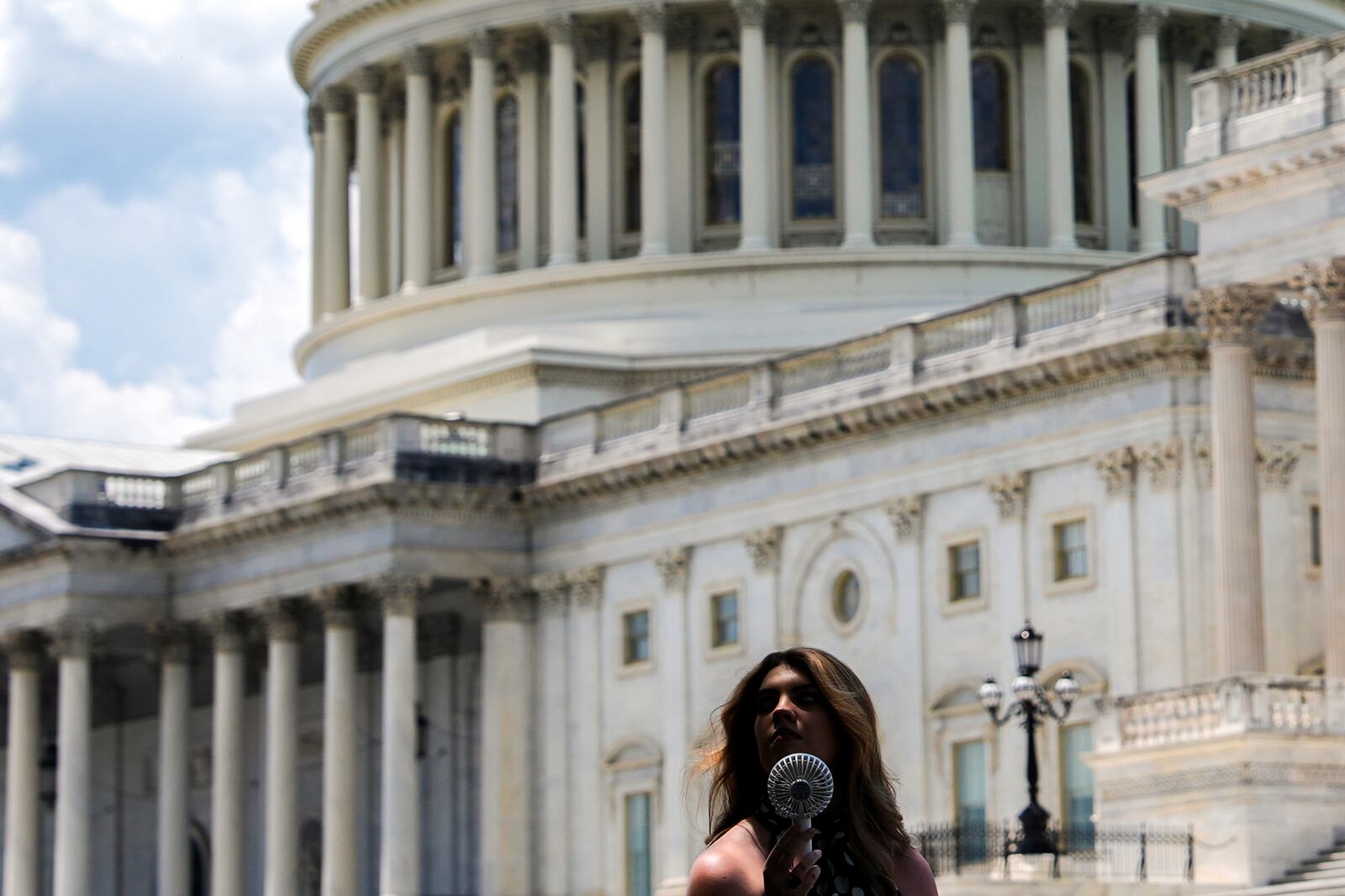 A woman uses a portable fan to cool down, Wednesday, June 25, 2025, outside the U.S. Capitol in Washington. (AP Photo/Julia Demaree Nikhinson)