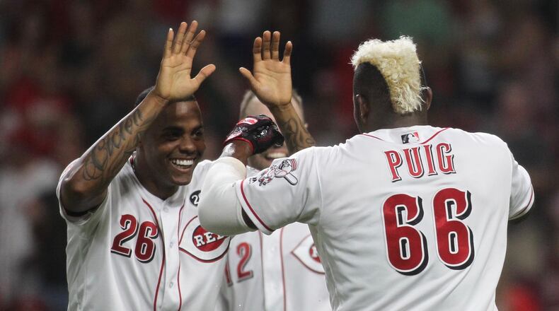 The Reds’ Raisel Iglesias, left, slaps hands with Yasiel Puig after a victory against the Brewers on Tuesday, July 2, 2019, at Great American Ball Park in Cincinnati. David Jablonski/Staff