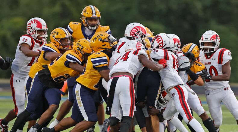 The Springfield football team pushes their teammate Jamil Miller and the Trotwood defense for extra yards as Miller carries the ball. BILL LACKEY/STAFF
