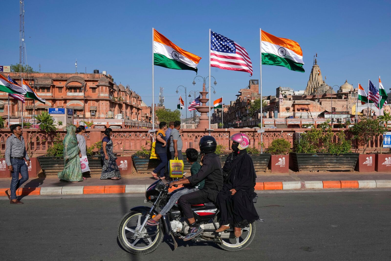 A family on a motorcycle watches Indian and US flags put up ahead of the US Vice President JD Vance visit in Jaipur, India, Monday, April 21, 2025. (AP Photo/Manish Swarup)