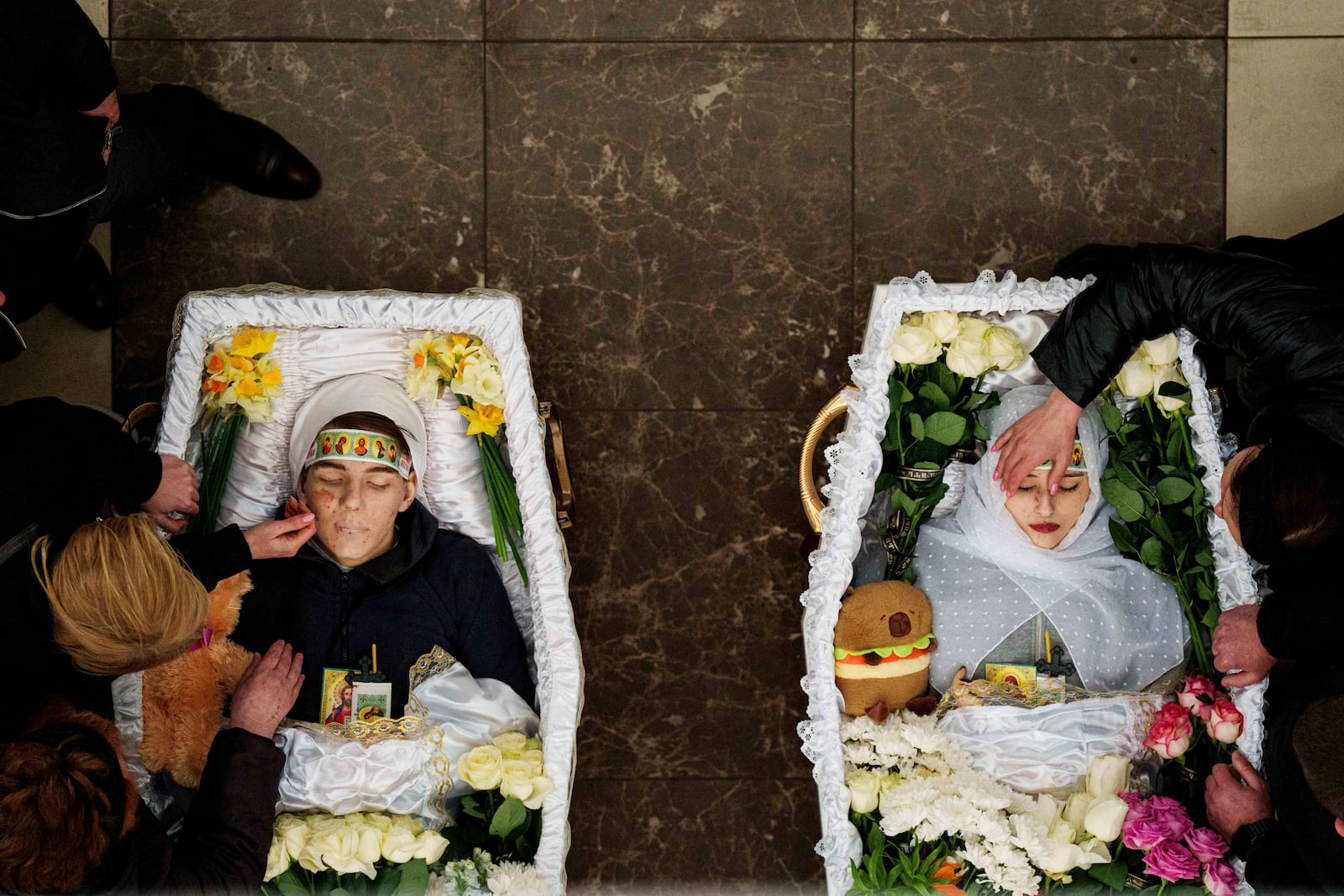 FILE- Mothers cries over the coffins of their children Danylo Nikittskyi, 15, and Alina Kutsenko, 15, killed by a Russian missile, during a funeral ceremony in Kryvyi Rih, Ukraine, April 7, 2025. (AP Photo/Evgeniy Maloletka, File)