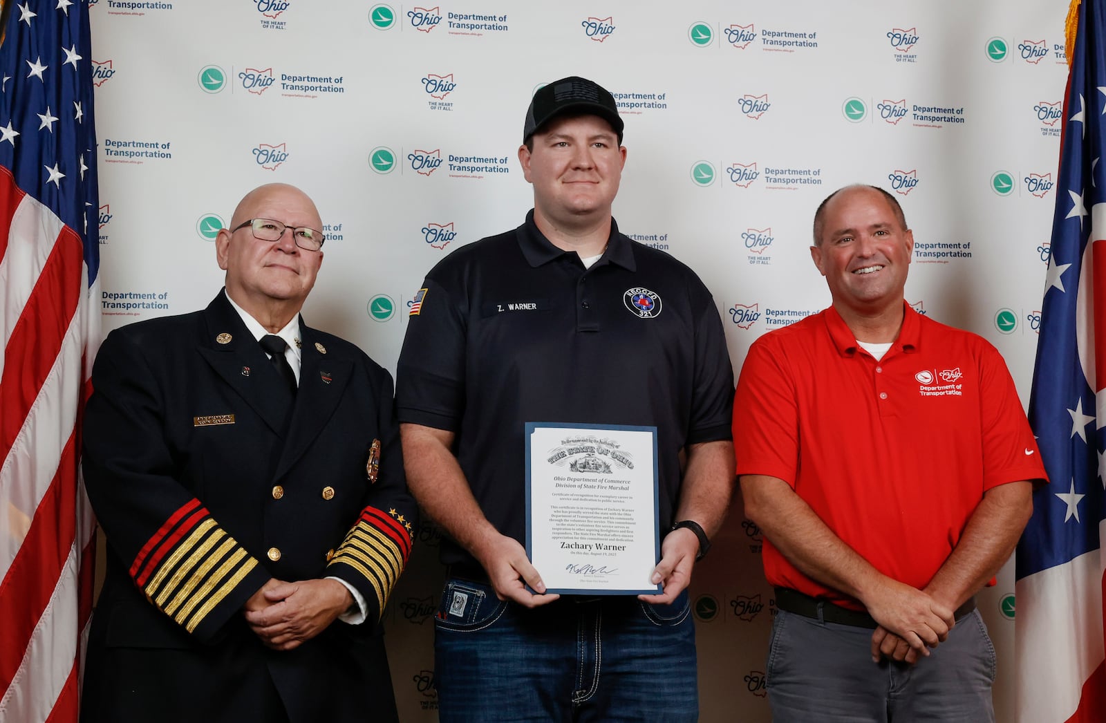 Zachary Warner, center, holds a certificate as he stands next to State Fire Marshal Kevin Reardon, left, and Mitch Blackford, ODOT Assistant Director of Field Operations, during an event honoring ODT employees who serve as volunteer firefighters or EMTs on Tuesday, August 19, 2025, at Clark State College. JOSEPH COOKE/STAFF