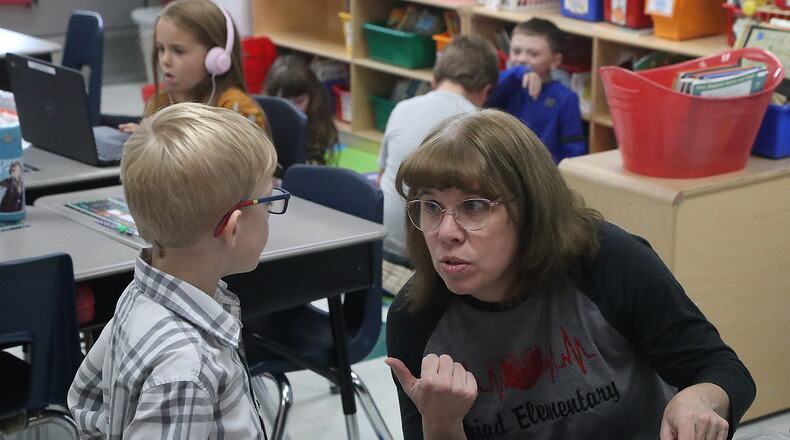 Schools in Clark and Champaign counties have reported an increase in COVID-19 cases from last week. Here, Diana Ferguson works with a student in her first grade class at Triad Elementary. BILL LACKEY/STAFF