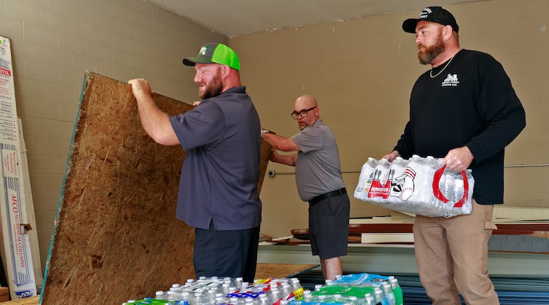 Casey Tingley, president of Ohio Hope Builders, left, Mark Houseman from Guardian Exteriors and Restoration, and Bryce White from Whites Family Fencing, unload supplies for the storm victims down south Tuesday, Oct. 1, 2024. BILL LACKEY/STAFF