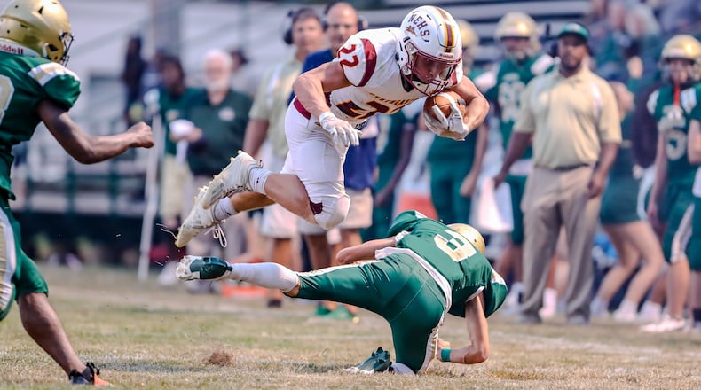 Northeastern High School senior Garrett Chadwell leaps over Catholic Central senior Owen Young during their game on Friday night at Hallinean Field in Springfield. The Jets won 20-7. Michael Cooper/CONTRIBUTED