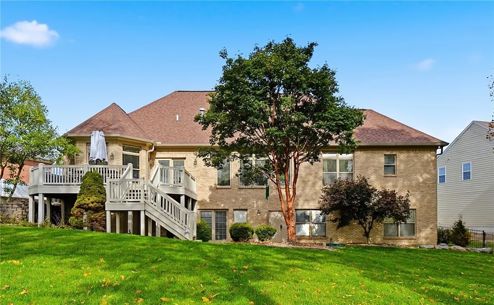 The back of the home features an elevated wood deck with railings and a partially covered lower level paver patio. CONTRIBUTED