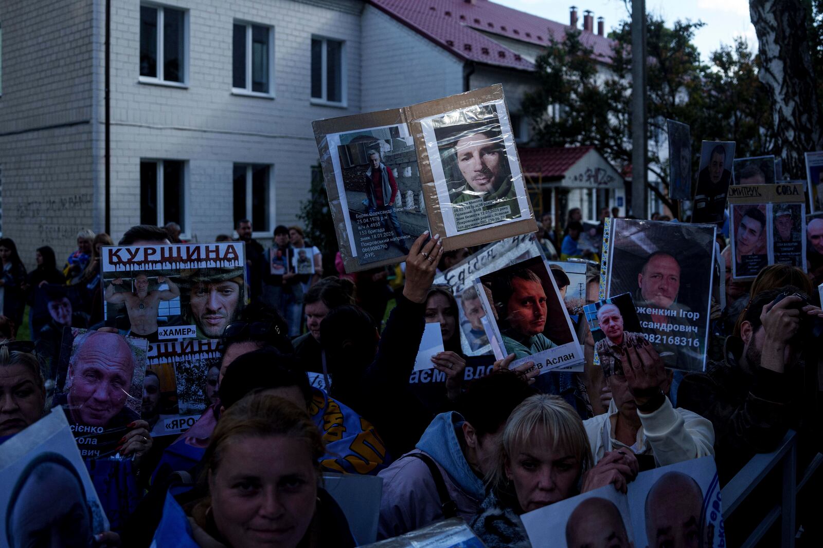 People hold photos of their missed relatives as Ukrainian soldiers return from captivity during a POWs exchange between Russia and Ukraine, in Chernyhiv region, Ukraine, Thursday, June 26, 2025. (AP Photo/Evgeniy Maloletka)