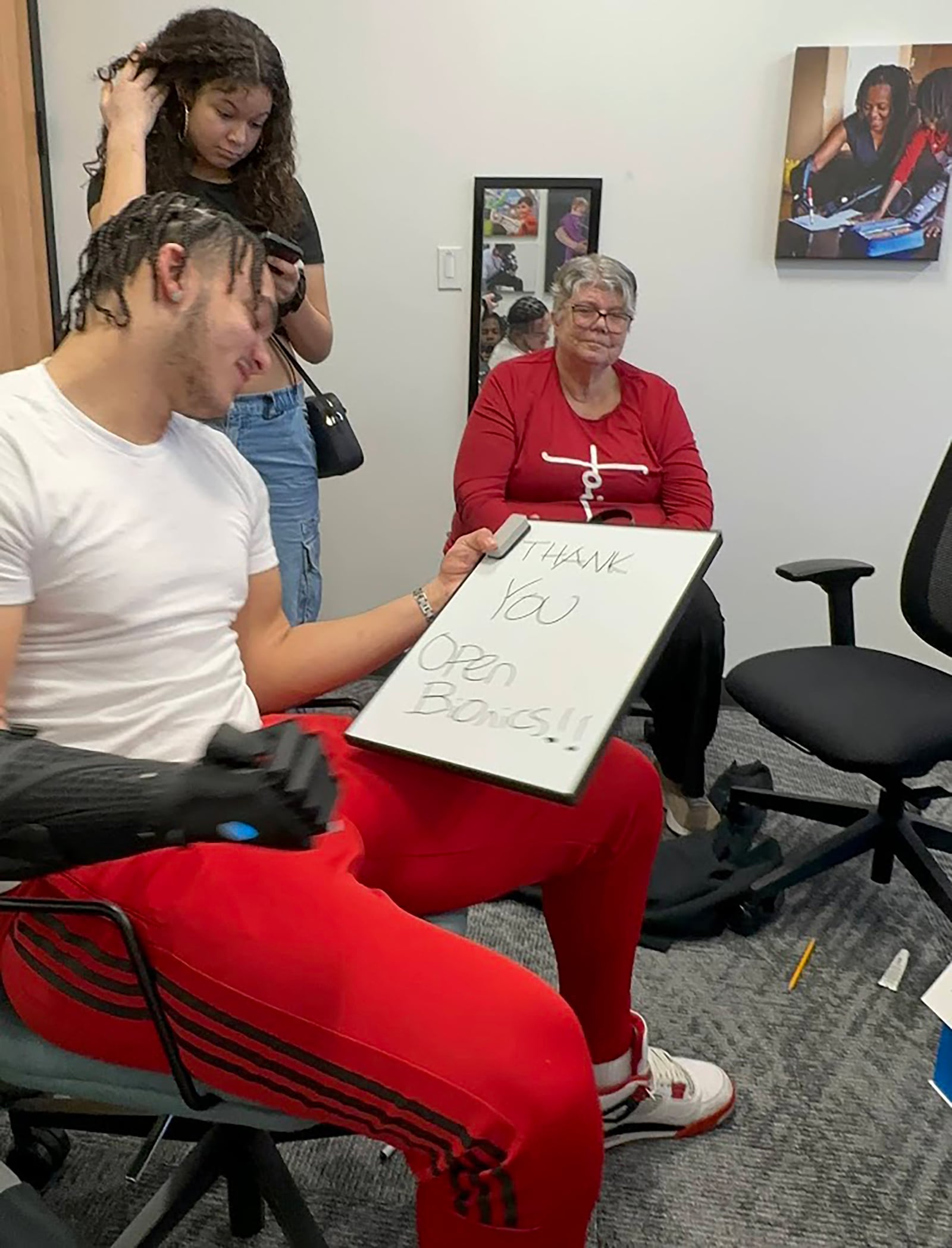 Issiah Evans tried out his new Bionic hand in Orlando, writing with it for the first time in February 2024. His grandmother, Vickie Nelson, is shown in the background. CONTRIBUTED