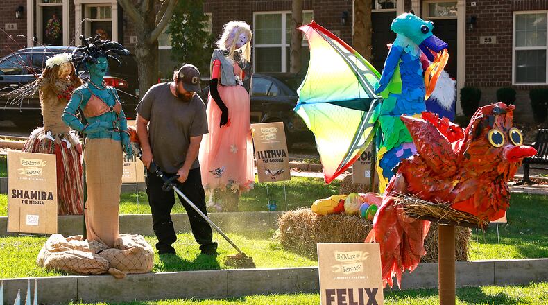 Sean Johnson, from Buena Vista Landscaping, trims the grass around the scarecrows that make up the Project Scare-A-Crow display in National Road Commons Park Wednesday, Oct. 9, 2024. BILL LACKEY/STAFF