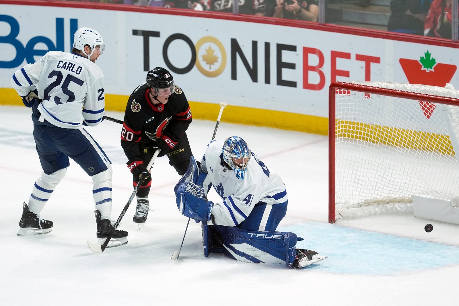 Ottawa Senators' Fabian Zetterlund (20) and Toronto Maple Leafs' Brandon Carlo (25) watch as the puck goes past Maple Leafs goaltender Anthony Stolarz (41) on a shot by Senators' Jake Sanderson (not shown) during overtime of Game 4 of an NHL hockey Stanley Cup first-round playoff series in Ottawa, Ontario, Saturday, April 26, 2025. (Adrian Wyld/The Canadian Press via AP)