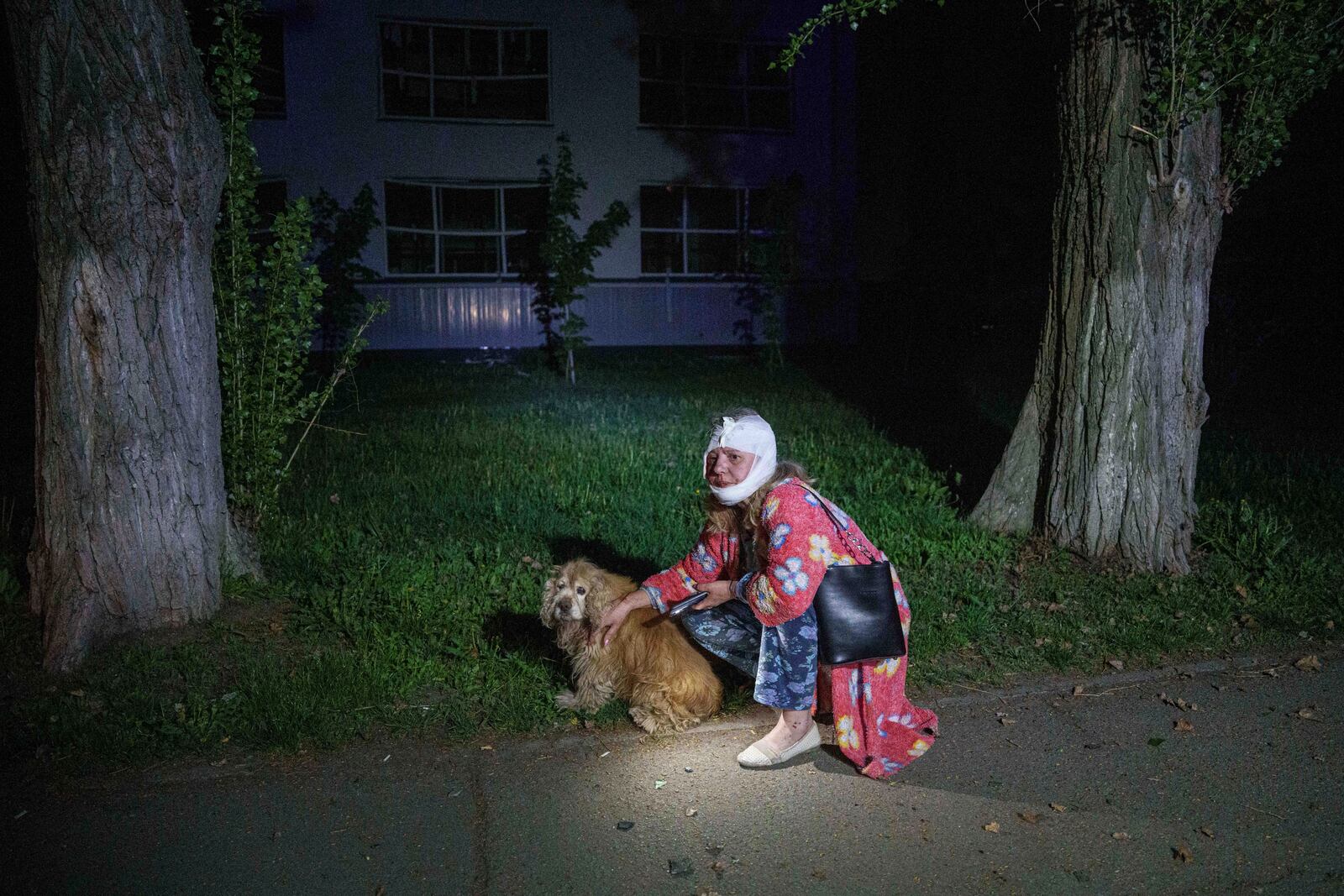 An injured woman sits with her dog near a house destroyed by a Russian airstrike in a residential neighborhood in Kyiv, Ukraine, on Thursday, April 24, 2025. (AP Photo/Evgeniy Maloletka)
