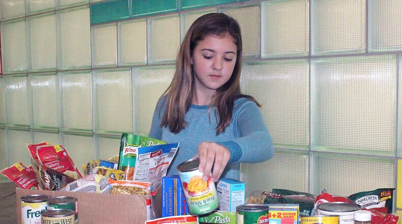 South Vienna School seventh grade student Trinity Ridgeway puts food items in the collection gathered by her peers. JEFF GUERINI/STAFF