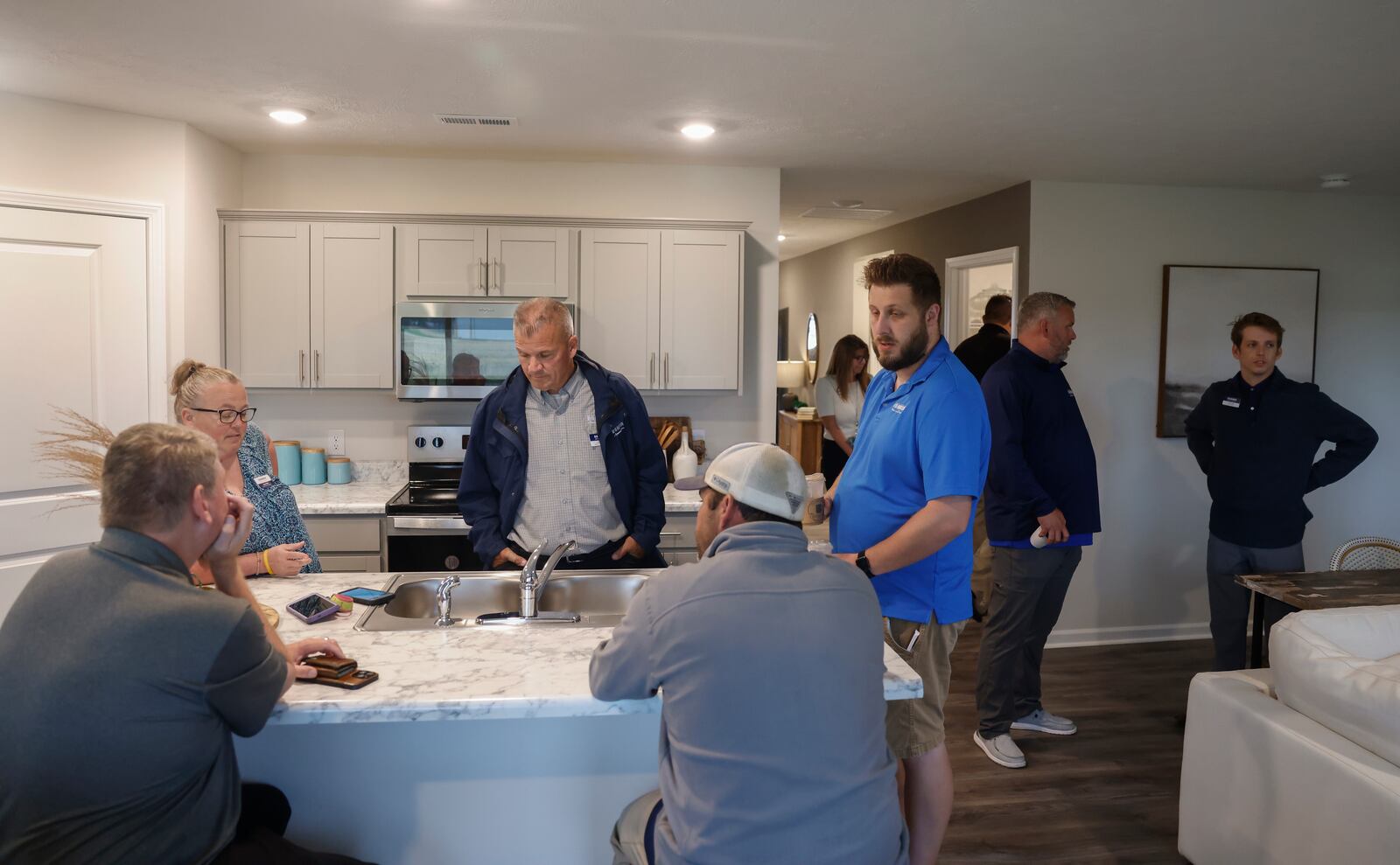 A group socializes and observes the kitchen and living room of a new home during the grand opening at Reserve at Honey Creek on Tuesday, May 20, 2025, in New Carlisle. JOSEPH COOKE/STAFF
