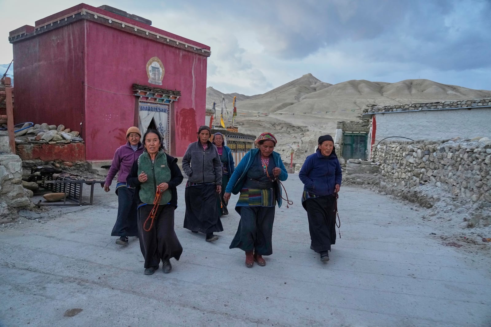 Women walk with prayers beads at the newly relocated settlement of the abandoned Samjung village in the Mustang region, 462 kilometers (288 miles) west of Kathmandu, Nepal, Saturday, April 19, 2025. (AP Photo/Niranjan Shrestha)