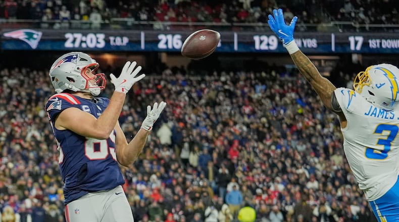 New England Patriots tight end Hunter Henry, left, catches a pass next to Los Angeles Chargers safety Derwin James Jr. (3) and carries it in for a touchdown in the second half of an NFL wild-card playoff football game in Foxborough, Mass., Sunday, Jan. 11, 2026. (AP Photo/Robert F. Bukaty)