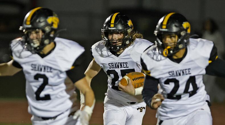 Shawnee's TJ Meeks carries the ball behind his teammates Conner Earles and Braylon Brim during Friday's playoff game. BILL LACKEY/STAFF