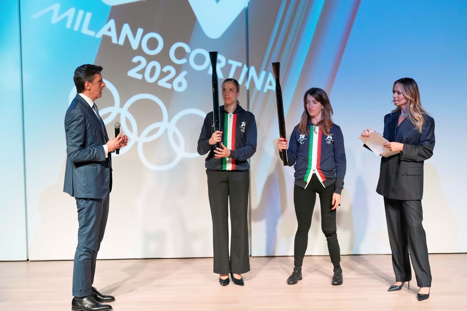 Italian figure skaters, Carolina Kostner, center left, and Valentina Marchei, center right, hold the Torches for the Olympic and Paralympic Winter Games Milano Cortina 2026 during the official unveiling ceremony at Italian Pavilion of Osaka Expo 2025 in Osaka, western Japan, Monday, April 14, 2025. (AP Photo/Hiro Komae)