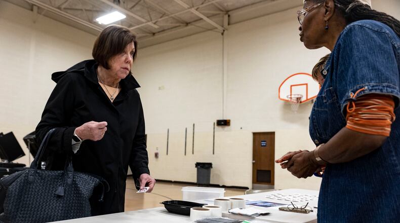 FILE - Marcia Carroll, 72, of Perrysburg takes an Ohio voting sticker at the Woodland Elementary School Polling location in Perrysburg, Ohio, on Tuesday May 3, 2022.  The great vote-by-mail wave appears to be receding just as quickly as it arrived. After tens of millions of Americans opted for mail ballots during the pandemic election of 2020, voters in the early primary states are returning in droves to in-person voting. (Stephen Zenner/The Blade via AP, File)